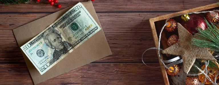 Twenty dollar bill on top of wood background with box of Christmas decorations off to the side