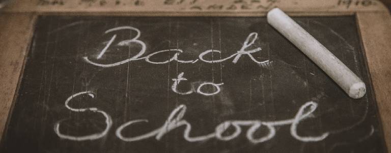 The words "back to school" are scripted in chalk on a small black blackboard.