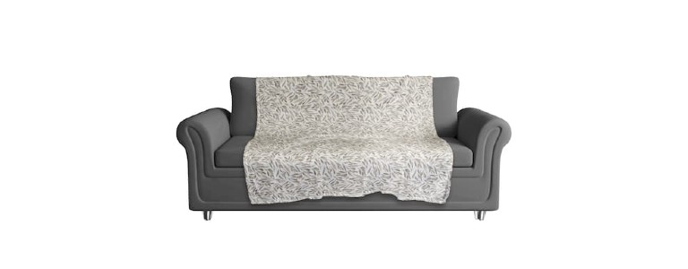 A greige leaf-printed blanket draped over a grey couch