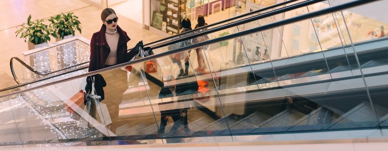 A female shopper going up a mall escalator