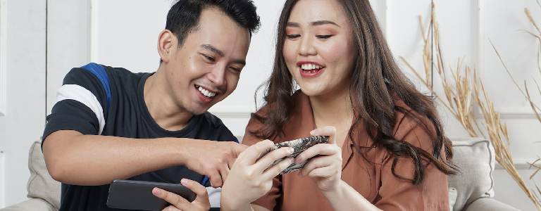 A couple holding their smartphones and smiling.