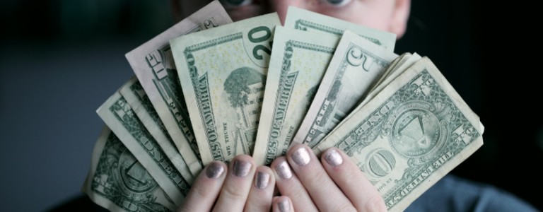 Woman holding up several dollar bills