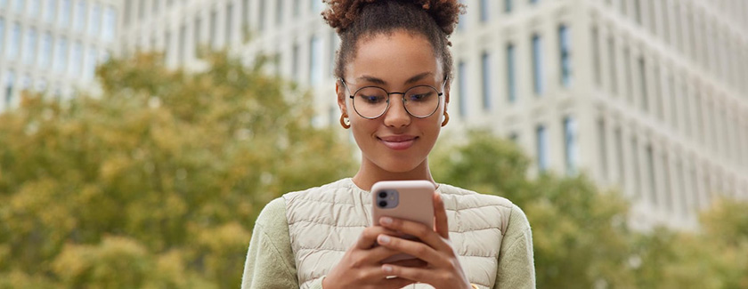 Woman looking down at mobile phone outside and smiling