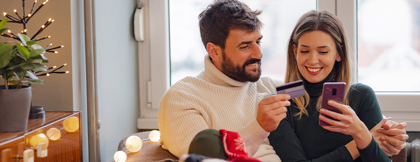 Man holding credit card with woman on her phone