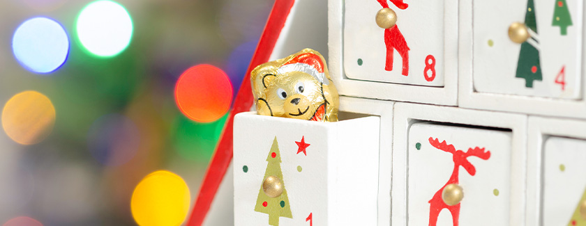 Gold foil-wrapped chocolate teddy bear peeping out of Day 1 drawer of advent calendar
