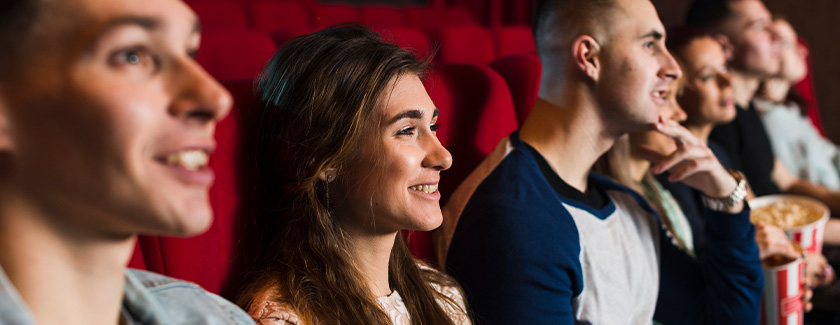 A row of friends sitting in the cinema, smiling at the screen