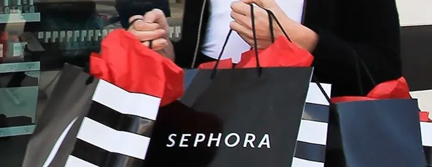 Woman holding three Sephora shopping bags outside